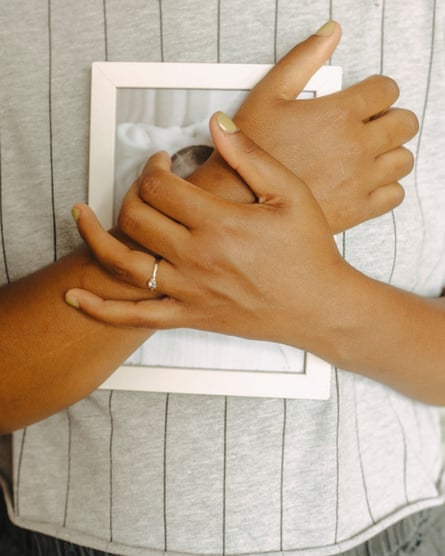 Poppy Noor’s hands clutching an obscured photograph of her son Mo to her chest