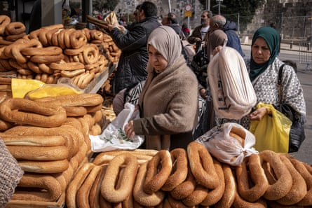 Two women in scarves surrounded by bread.