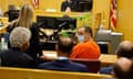 Man in orange jump suit and mask in court