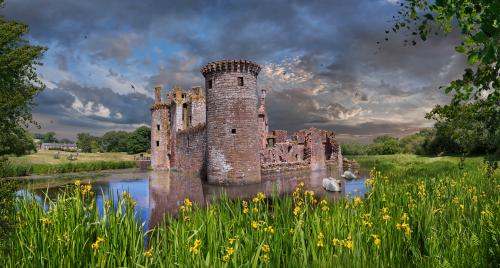 Castle ruins surrounded by moat with daffodils in front