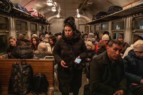 A woman stands among other passengers on a train