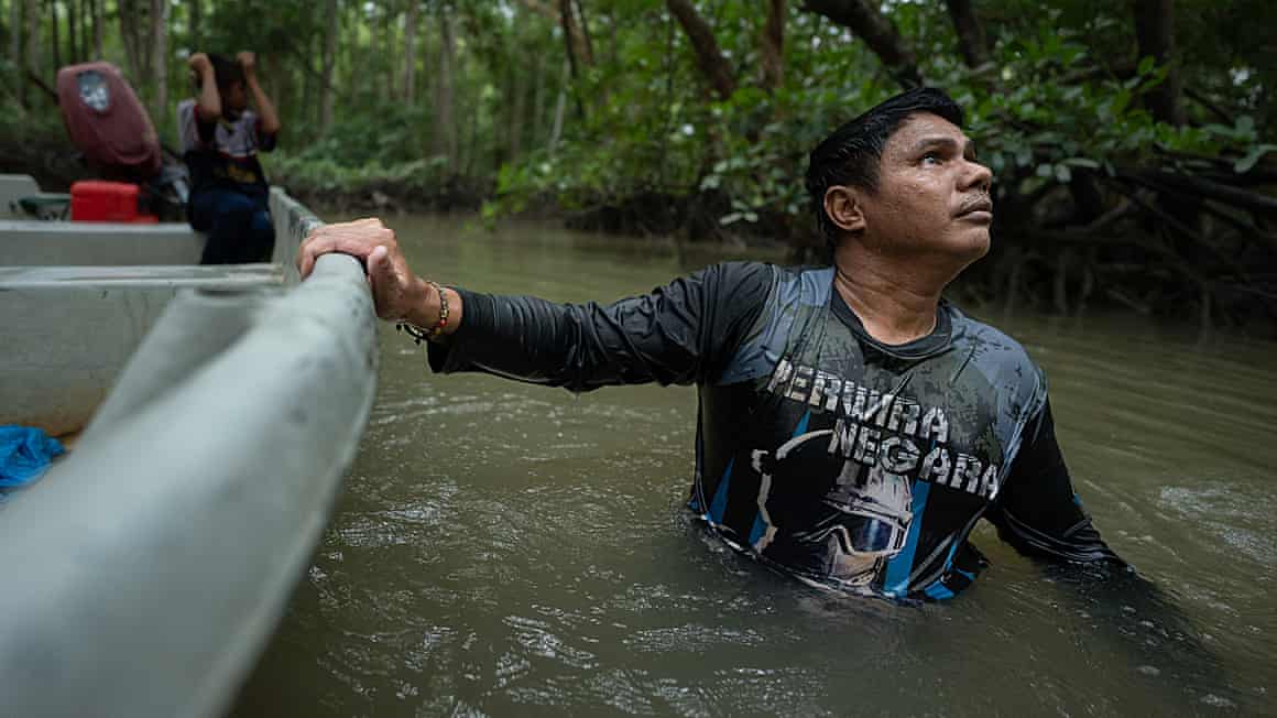 Man wading through water holding on to his boat