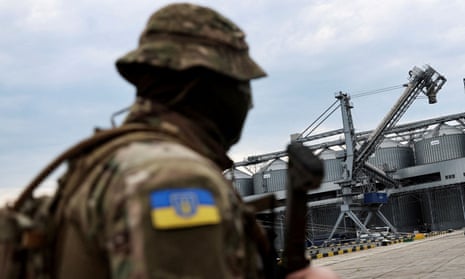 A Ukrainian serviceman in front of grain silos at the Black Sea port of Odesa in July