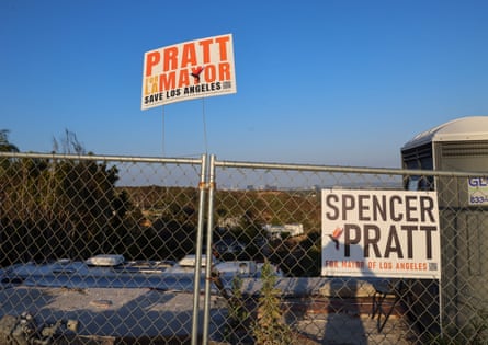 Signs on a fence next to a burnt-down house.