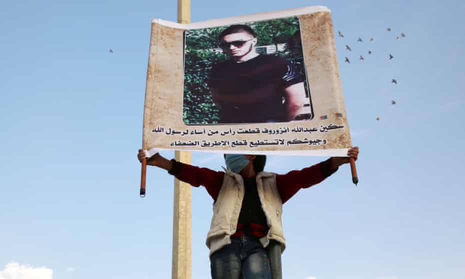 A demonstrator raises a portrait of Abdullakh Anzorov during a protest calling for a boycott of French goods in Idlib in October 2020. The writing below the portrait reads in Arabic: ‘The knife of Anzorov cut the head of that who offended the Prophet of God, their armies are only able to cut the road of the poor.’