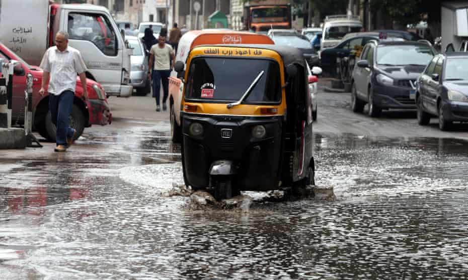 A taxi drives through a flooded street in Cairo