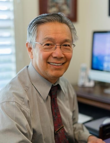 A smiling grey-haired man at a desk
