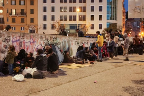 A row of people sit on the pavement against a wall in Martyrs' Square in Beirut.