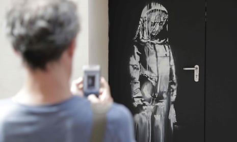 A man takes a photograph of an artwork by street artist Banksy in Paris on a side street to the Bataclan concert hall where a terrorist attack killed 90 people in November 2015.