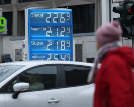 A car and a pedestrian pass by a petrol station that shows gasoline prices in Berlin, Germany.
