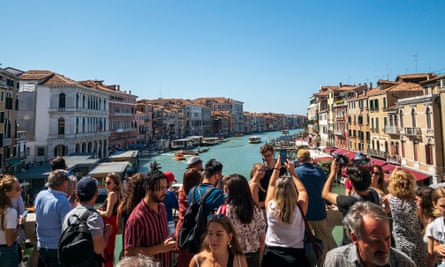 Tourists crowd the Rialto Bridge, overlooking the Grand Canal