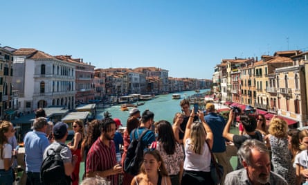 The famous Rialto Bridge in Venice is crowded with tourists.
