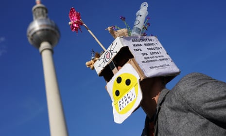 A man wears a box that reads: ‘Do you need Mama Merkel? Papa Drosten? Grandpa Gates? Or are you still capable of independent thinking?’ during a protest in Berlin against lockdown measures.