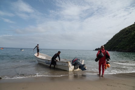 Three men pull a fishing boat on to the beach