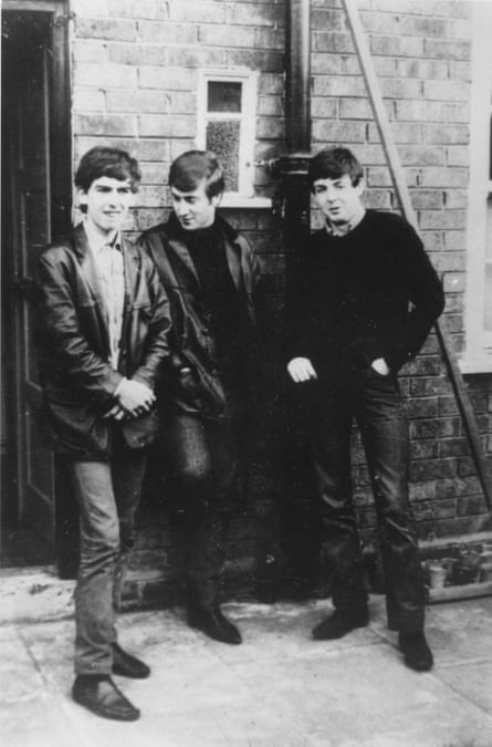 A black and white photograph of three young men all dressed in black standing in front of a house