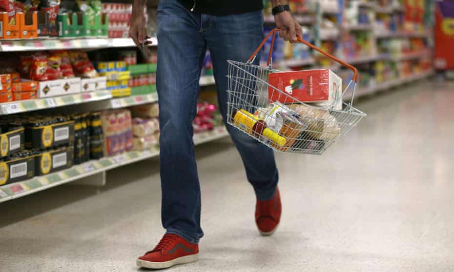 A shopper carries a basket in a supermarket in London
