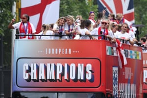 England’s Chloe Kelly takes a selfie with Leah Williamson, holding the Euros trophy, on the top deck of an open doubledecker bus with team mates