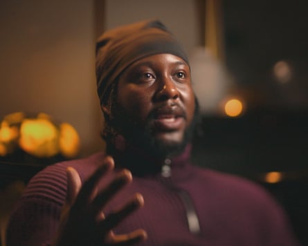 A man in a burgundy top and a brown hat sits for an interview