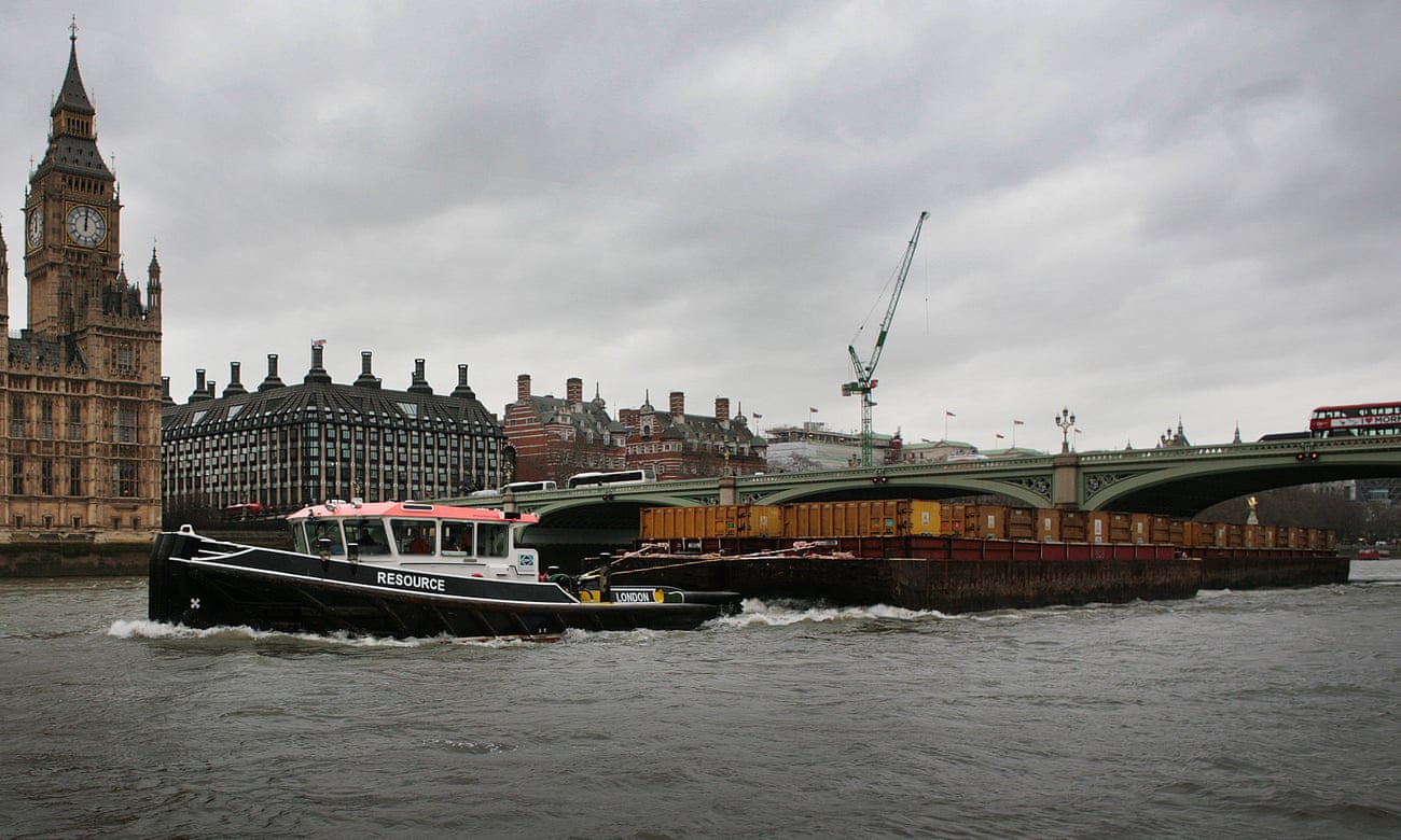 A barge towing containers passes under Westminster Bridge.