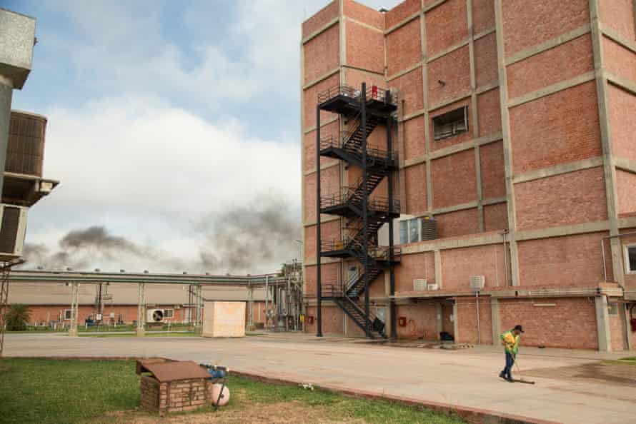 A man sweeps a yard outside a windowless six-storey red-brick building