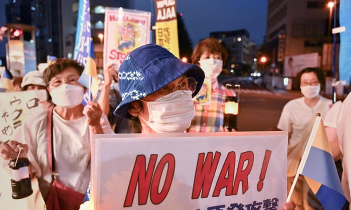 People attend a small protest holding placards and candles near the Russian Embassy in Tokyo.
