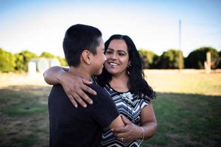 Fidelia Morales hugging her son Junior in their backyard that is surrounded by orange tress on all sides.