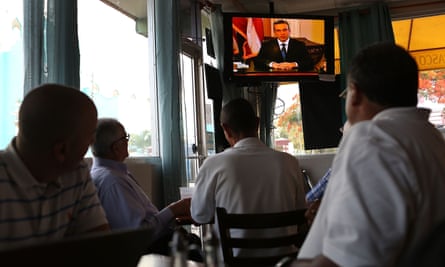 People listen as Puerto Rican governor Alejandro Garcia Padilla addresses the island’s residents in a televised broadcast regarding the governments $72bn debt.