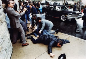 A secret service agent, left, draws his gun after an assassination attempt on President Ronald Reagan left White House press secretary James Brady, police officer Thomas Delahanty, and secret service agent Tim McCarthy injured.