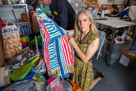 A blond woman in a black and yellow dress holding up a red white and blue stripy dress