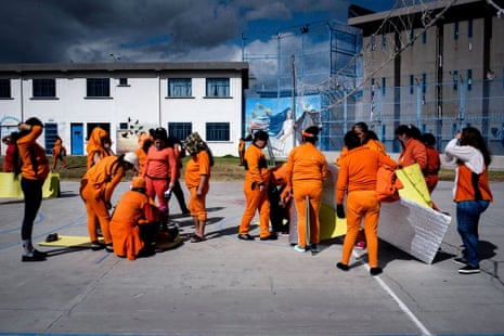 Women in orange prison clothes gather in a yard
