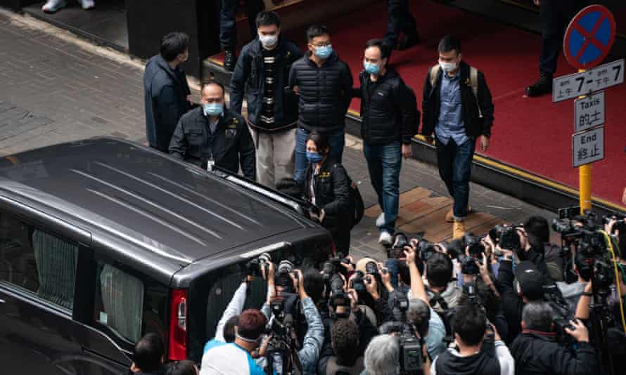 The Stand News editor-in-chief is brought into a vehicle after police searched the premises at the independent news outlet office on 29 December