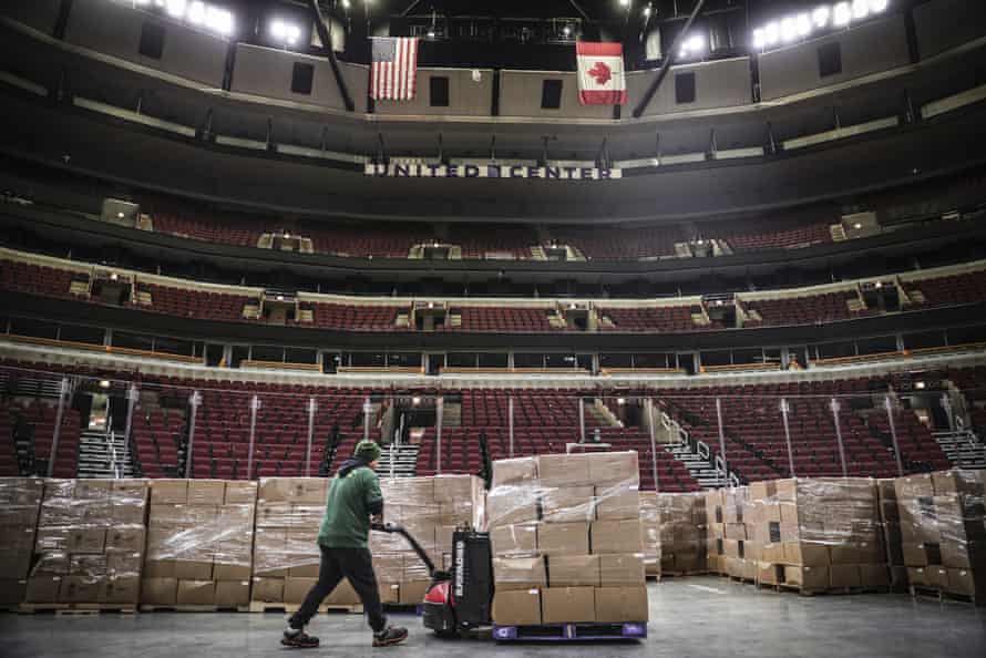 In this March 20, 2020 photo provided by the United Center, a worker moves food onto the floor of the United Center in Chicago. The Greater Chicago Food Depository, Chicago’s food bank, will be utilizing the United Center as a satellite storage facility in response to the increased need for food during the coronavirus pandemic.