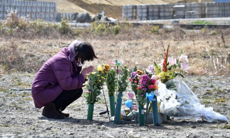 A woman prays for victims on the sixth anniversary of the 2011 quake-tsunami disaster in Namie, a no-entry zone in Fukushima prefecture.