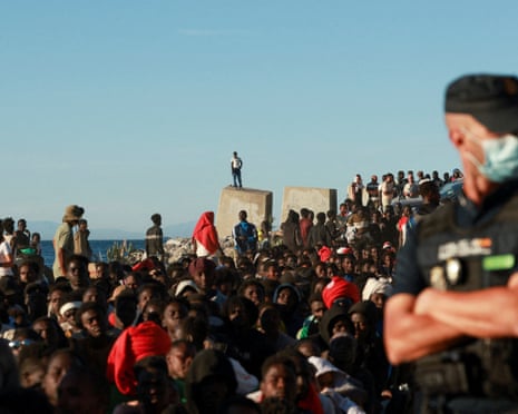 Migrants wait in line to receive food and beverage from the Red Cross, following mass crossings of migrants on foot and by sea from Morocco into Spanish territory, in Ceuta, Spain.