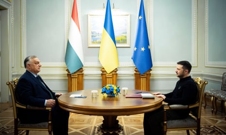 The Ukrainian president, Volodymyr Zelenskiy  with the Hungarian prime minister, Viktor Orbán, seated opposite each other at a table with flags of Hungary, Ukraine and the EU in the background