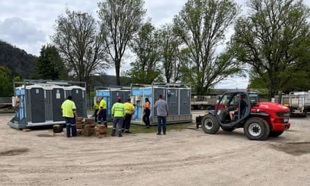 a row of portable showers and a forklift placing another