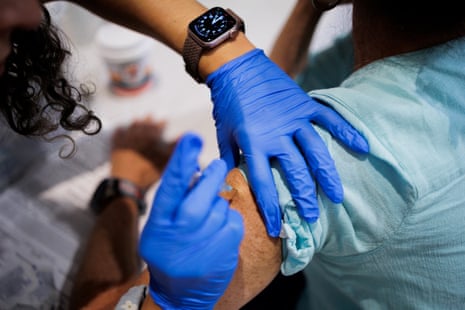 person with gloved hand administers vaccine
