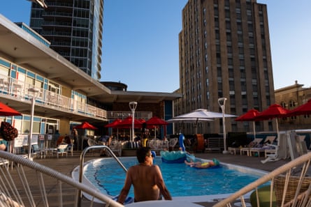 People socialize and enjoy the pool and drinks after work at the Unscripted Hotel rooftop patio which overlooks part of the city.