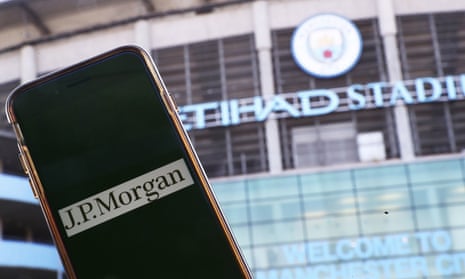 The logo of JP Morgan is seen on a phone screen adjacent to the Etihad stadium in Manchester.