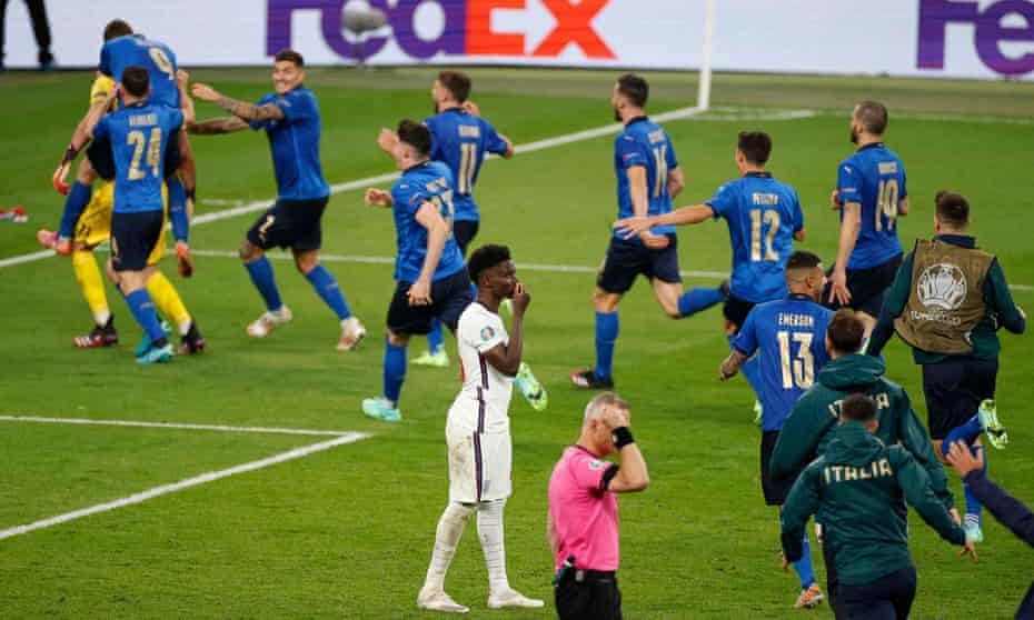 Italy’s players rush to celebrate with Gianluigi Donnarumma after he saved Bukayo Saka’s penalty.