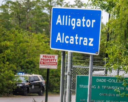 A constabulary car adjacent a plain bluish motion reference 'Alligator Alcatraz'