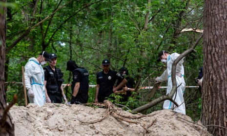 An excavation team and police work in a forest near Bucha, Ukraine to excavate bodies of Ukrainian civilians.