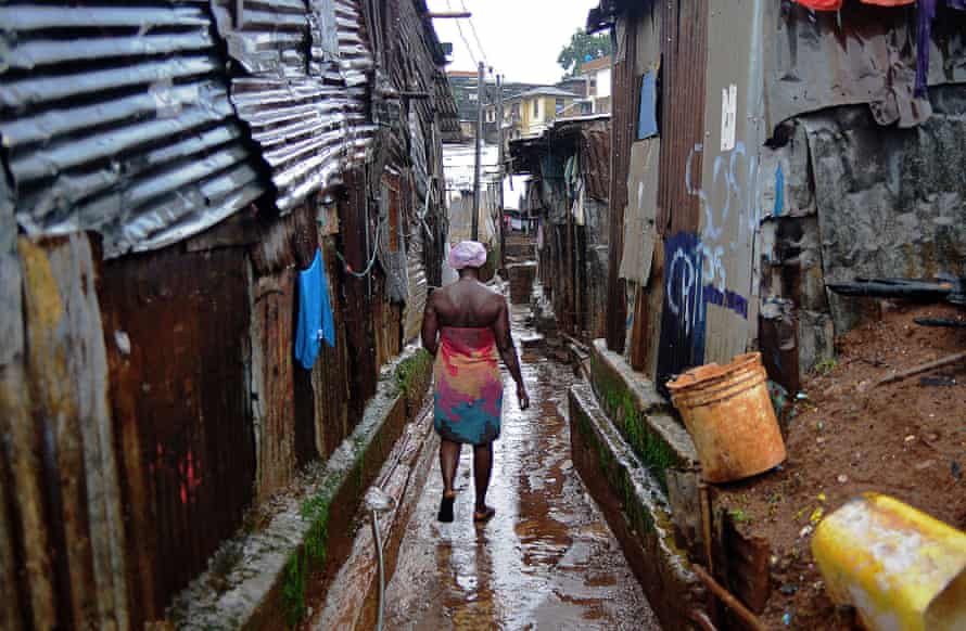 A woman walks through a slum in Freetown.