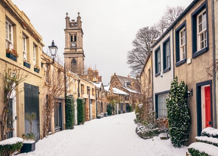 Snowy narrow lane with a church tower on the left