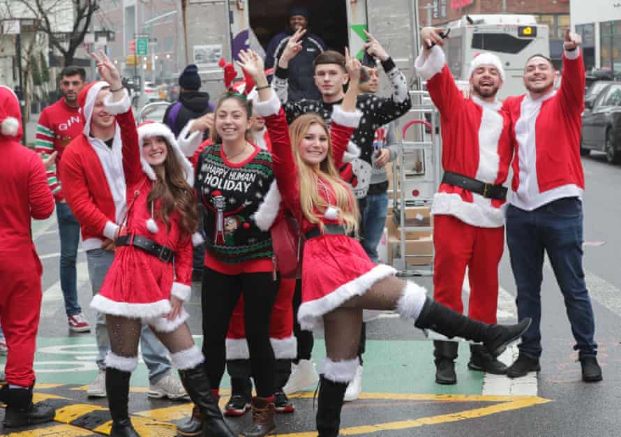 A group of people in Santa costumes pose for a picture on a street corner in New York City in 2019.