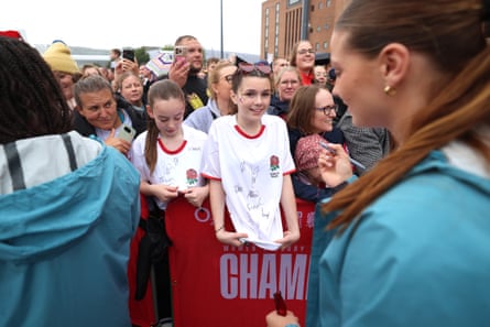 Young fans hold out their shirts for players of England to sign.