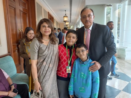 A woman and two young boys pose for a photograph alongside a man in a suit and glasses.