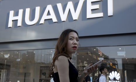 A woman uses a smartphone outside a Huawei store in Beijing