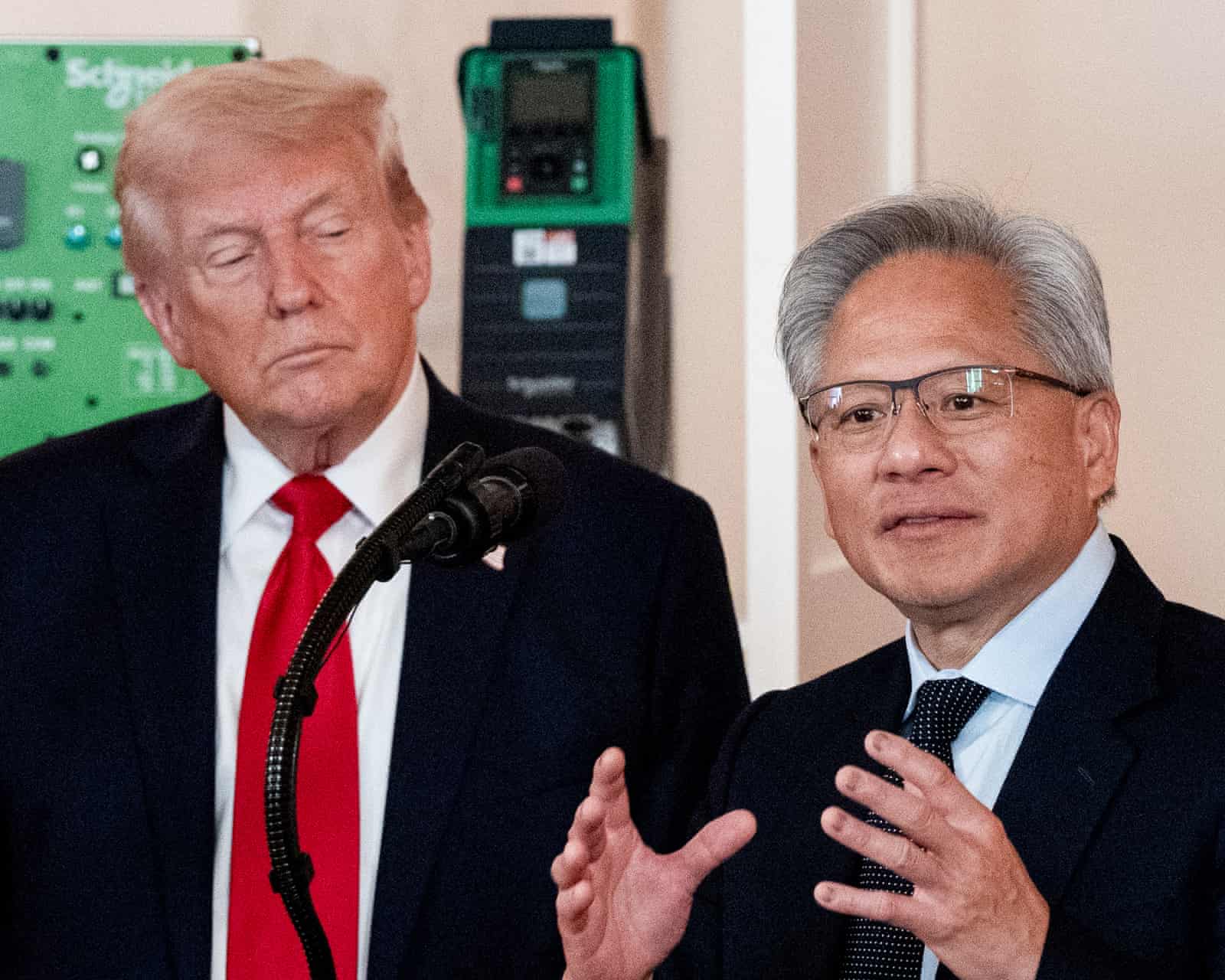 Two men in suits speak at podium