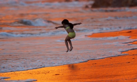 A child plays in surf reddened by the reflection of heavy smoke in Montecito, just south of Santa Barbara.